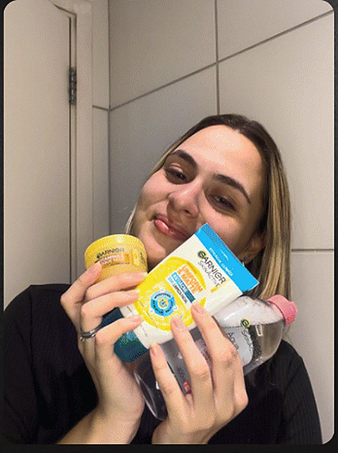 Julia segurando produtos de cuidado com a pele